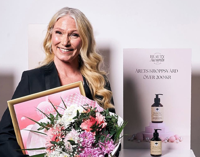 Naine, kes hoiab käes lillekimpu ja auhinda ning naeratab pidulikul hetkel.